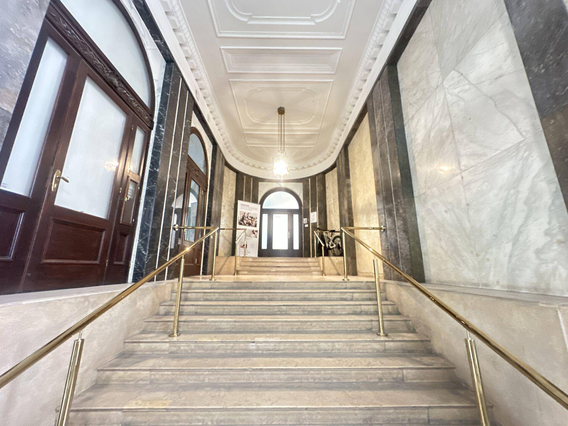 Elegantes Treppenhaus mit Marmorstufen und goldenen Handläufen, führt zu den oberen Etagen.
