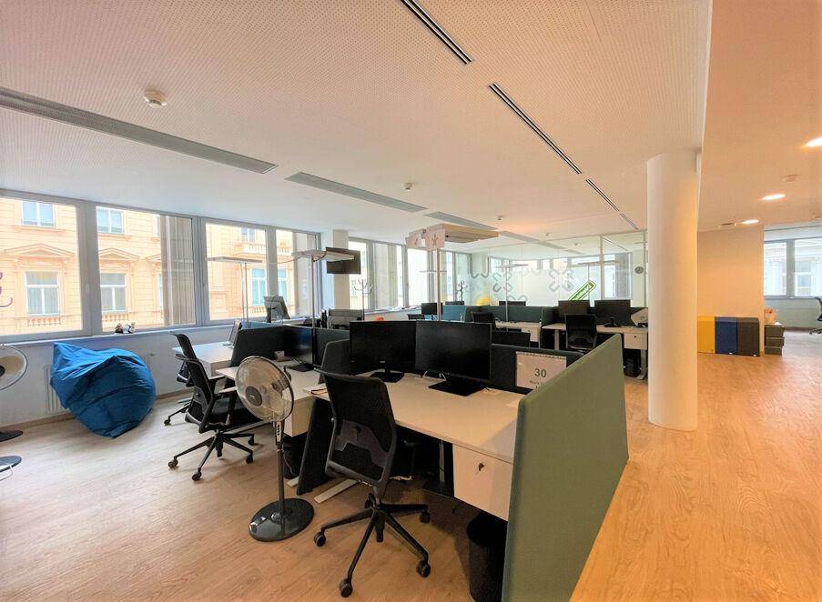 Großes, offenes Büro mit mehreren Arbeitsplätzen, Computern und hellen Holzfußböden.