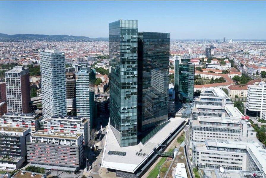 Eine Gruppe moderner Wolkenkratzer mit Glasfassaden dominiert die städtische Skyline unter blauem Himmel.