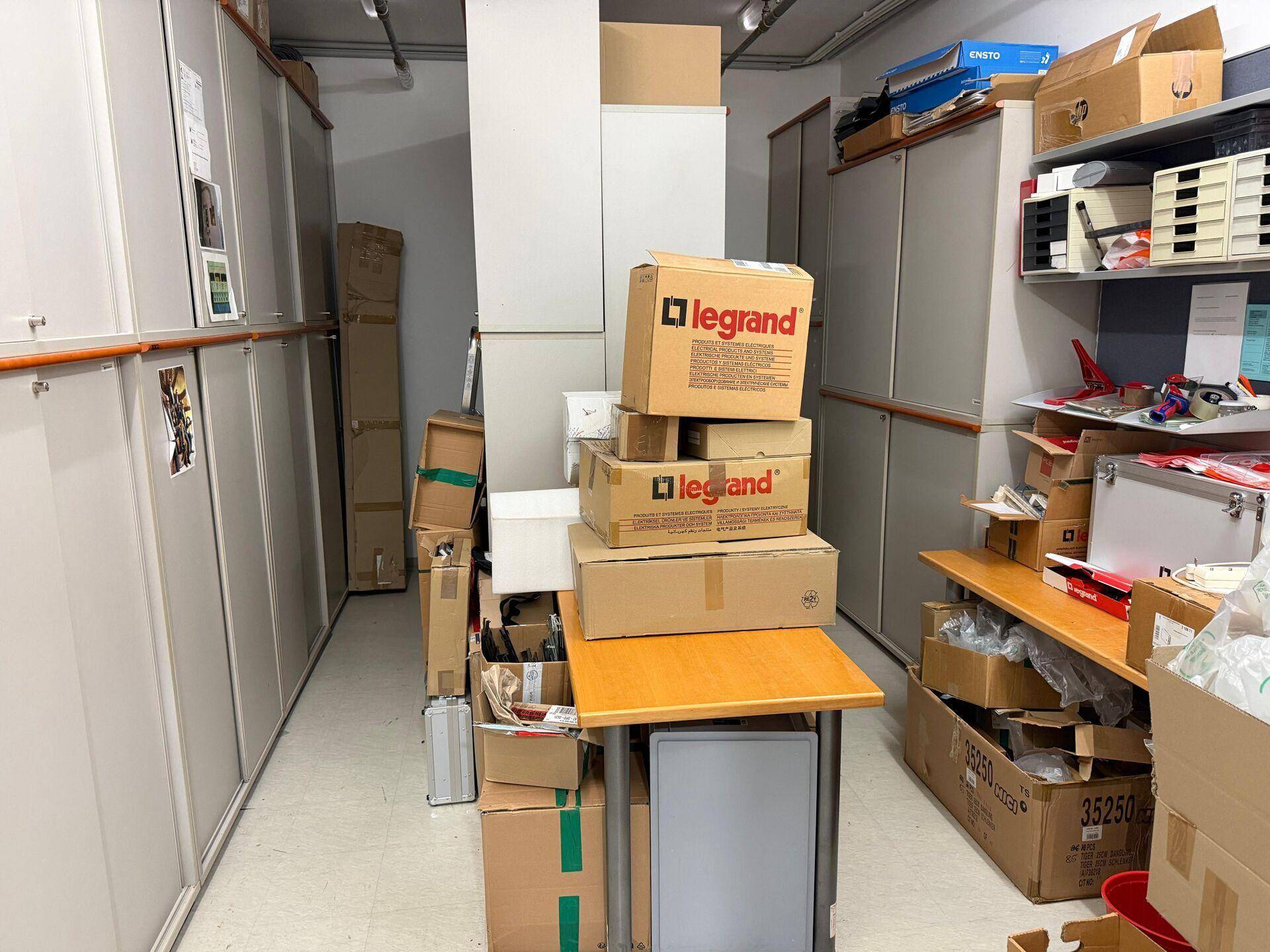 Lagerraum mit vielen Kartons, Regalen und Büromaterialien.