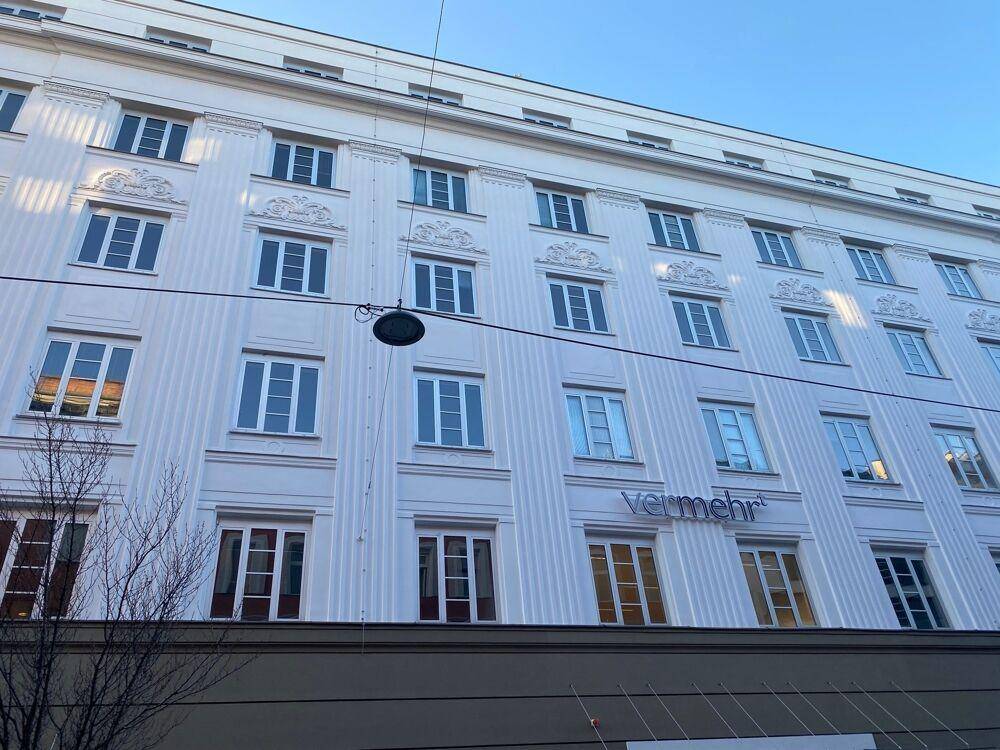 Ansicht der weißen Gebäudefassade mit zahlreichen Fenstern und dem Schriftzug "vermehr" im unteren Bereich.