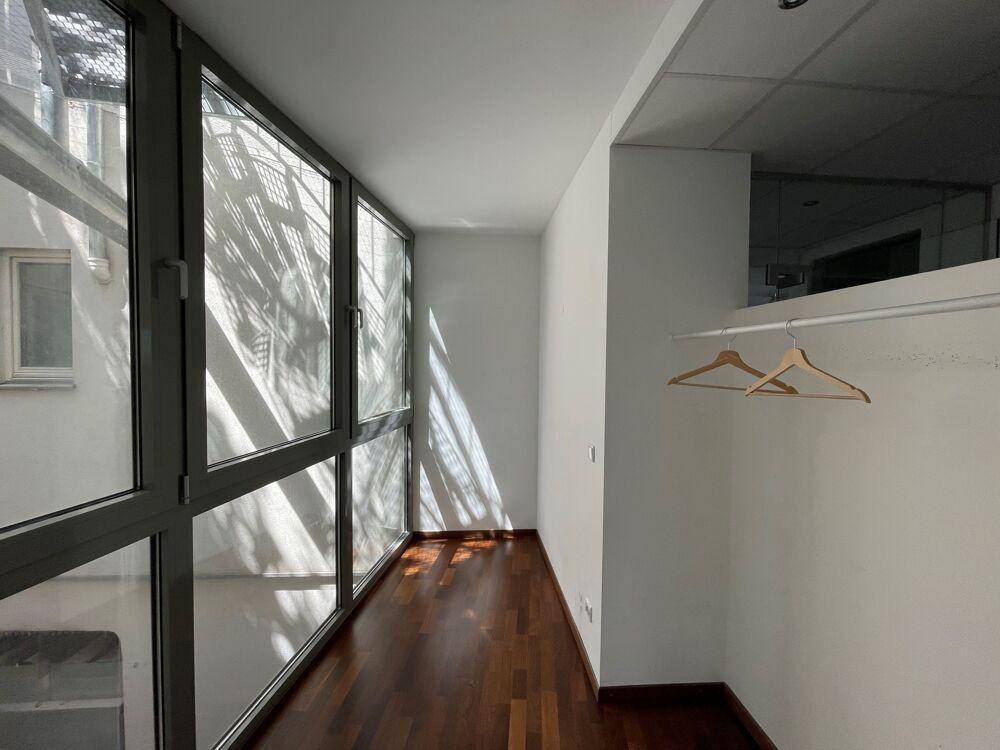 Heller Flur mit großen Fenstern, die viel Sonnenlicht hereinlassen, und Holzboden.