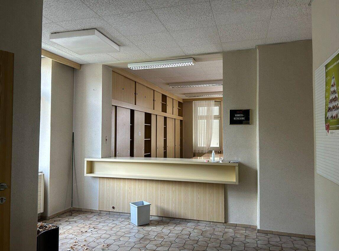 Empfangsbereich mit Theke, Einbauschränken und einem Fenster, das Tageslicht hereinlässt.