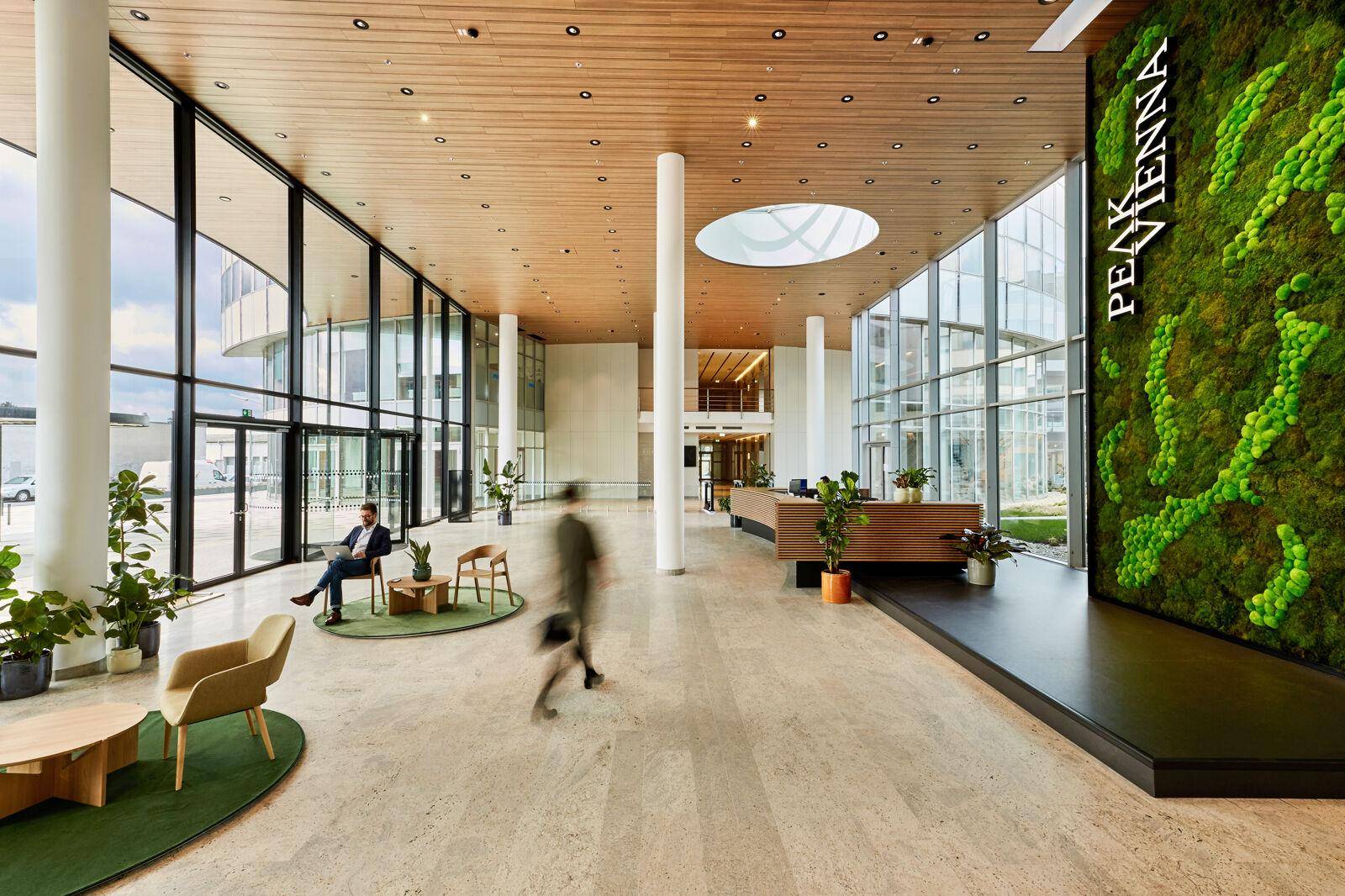 Elegante Lobby mit hohen Decken, großen Glasfronten und einer begrünten Wandinstallation.
