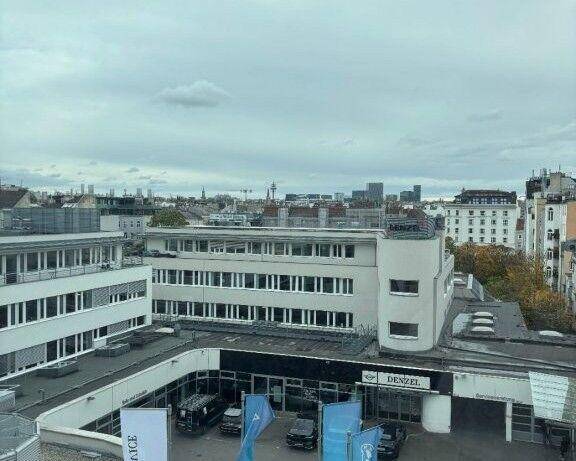 Luftaufnahme eines Geschäftsgebäudes mit umliegender Stadtlandschaft unter einem bewölkten Himmel.