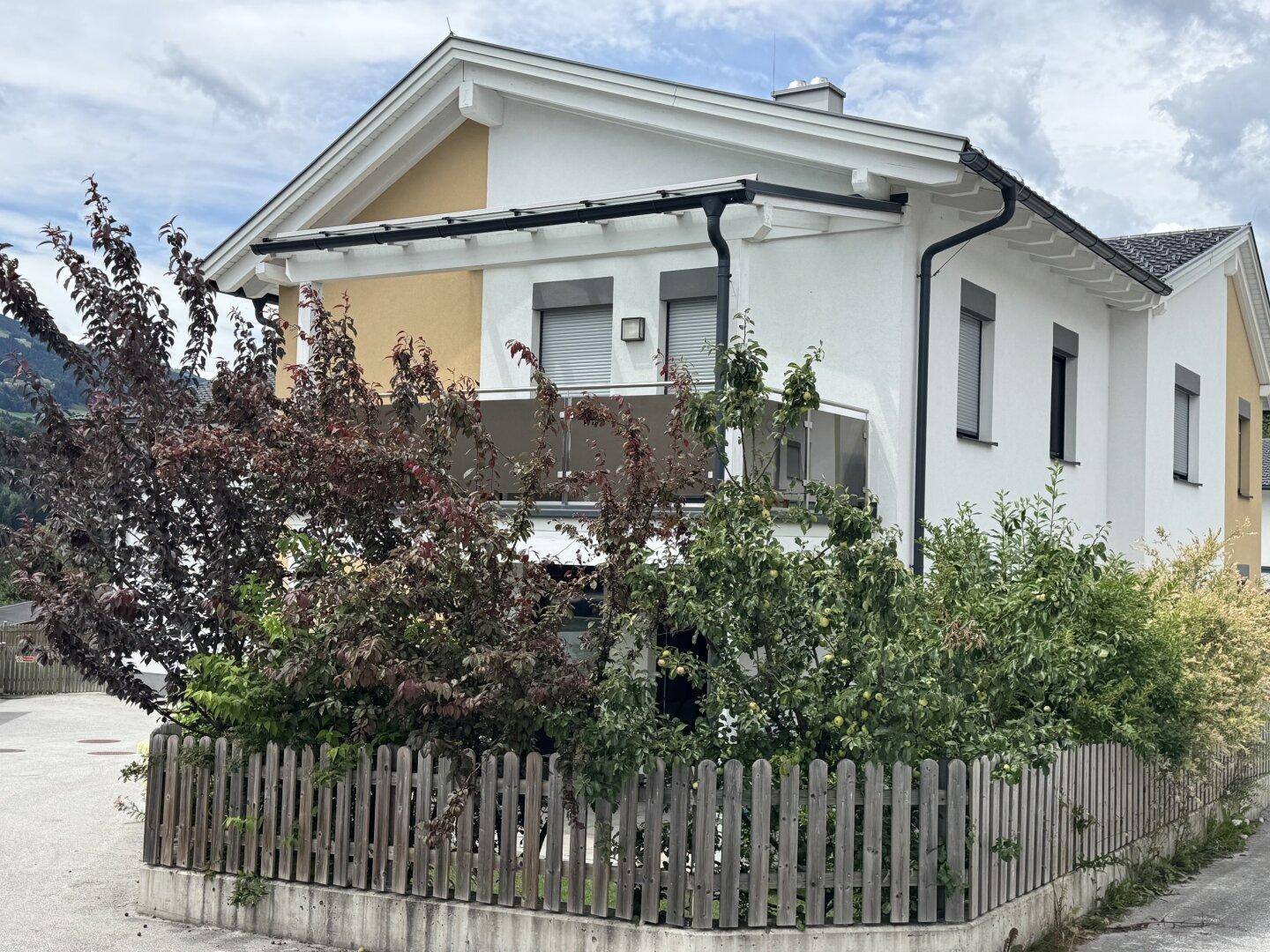 Ansicht des Hauses von der Seite mit Balkon und gepflegter grüner Umgebung.