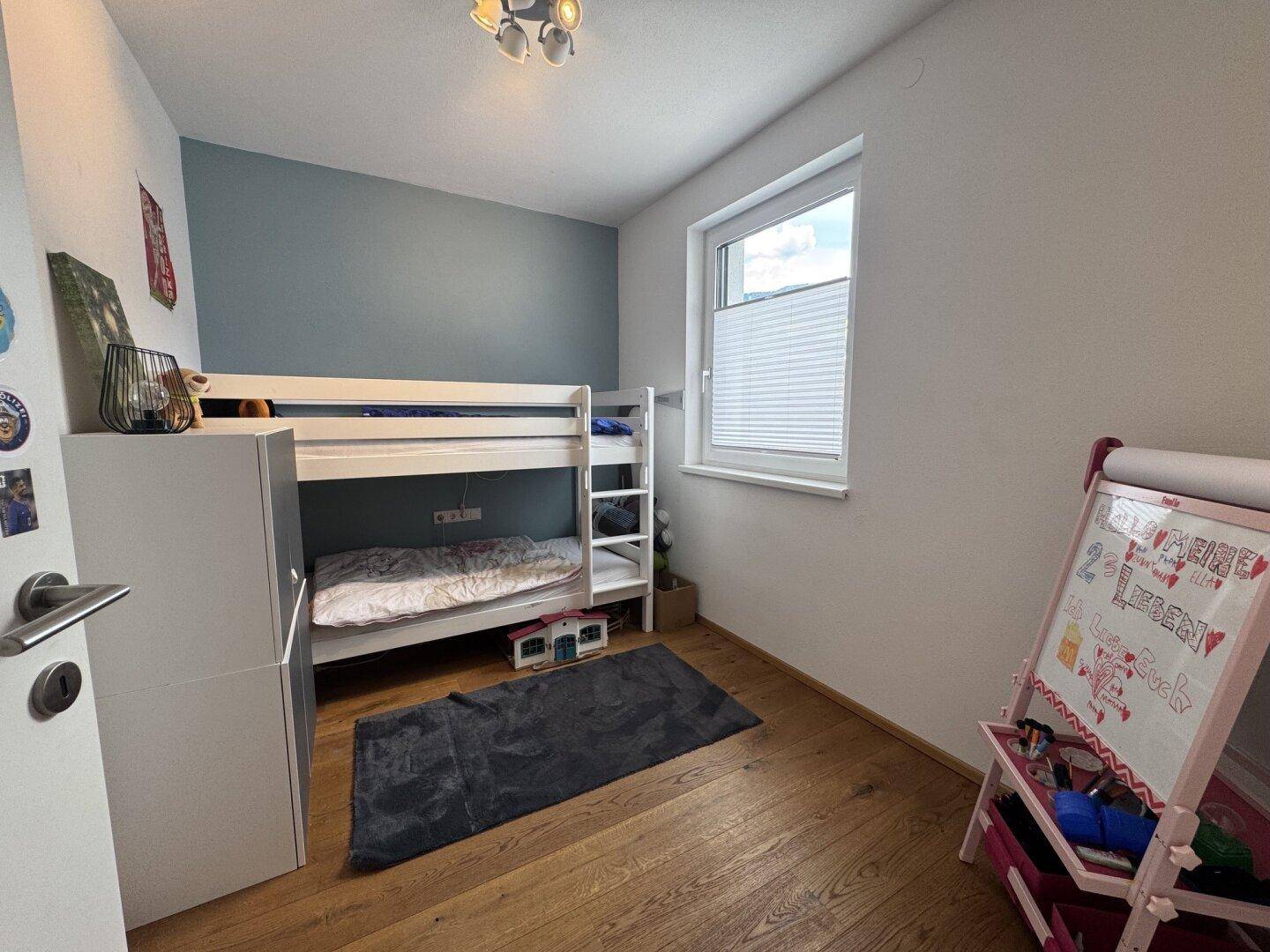 Kinderzimmer mit Etagenbett, Holzboden und Fenster, ideal für Geschwister oder Gäste.