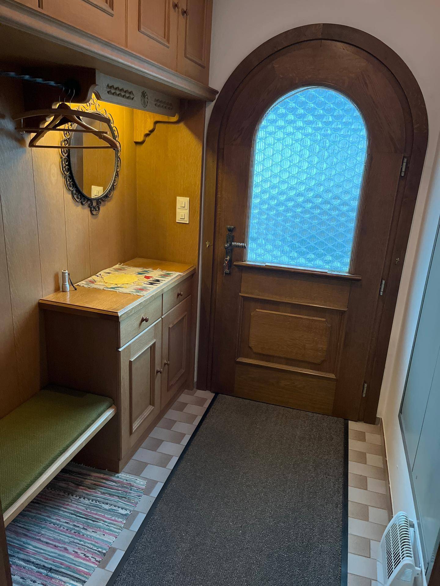 Gemütlicher Eingangsbereich mit Holztür, Einbauschrank und Sitzbank, typisch für ein traditionelles Haus.