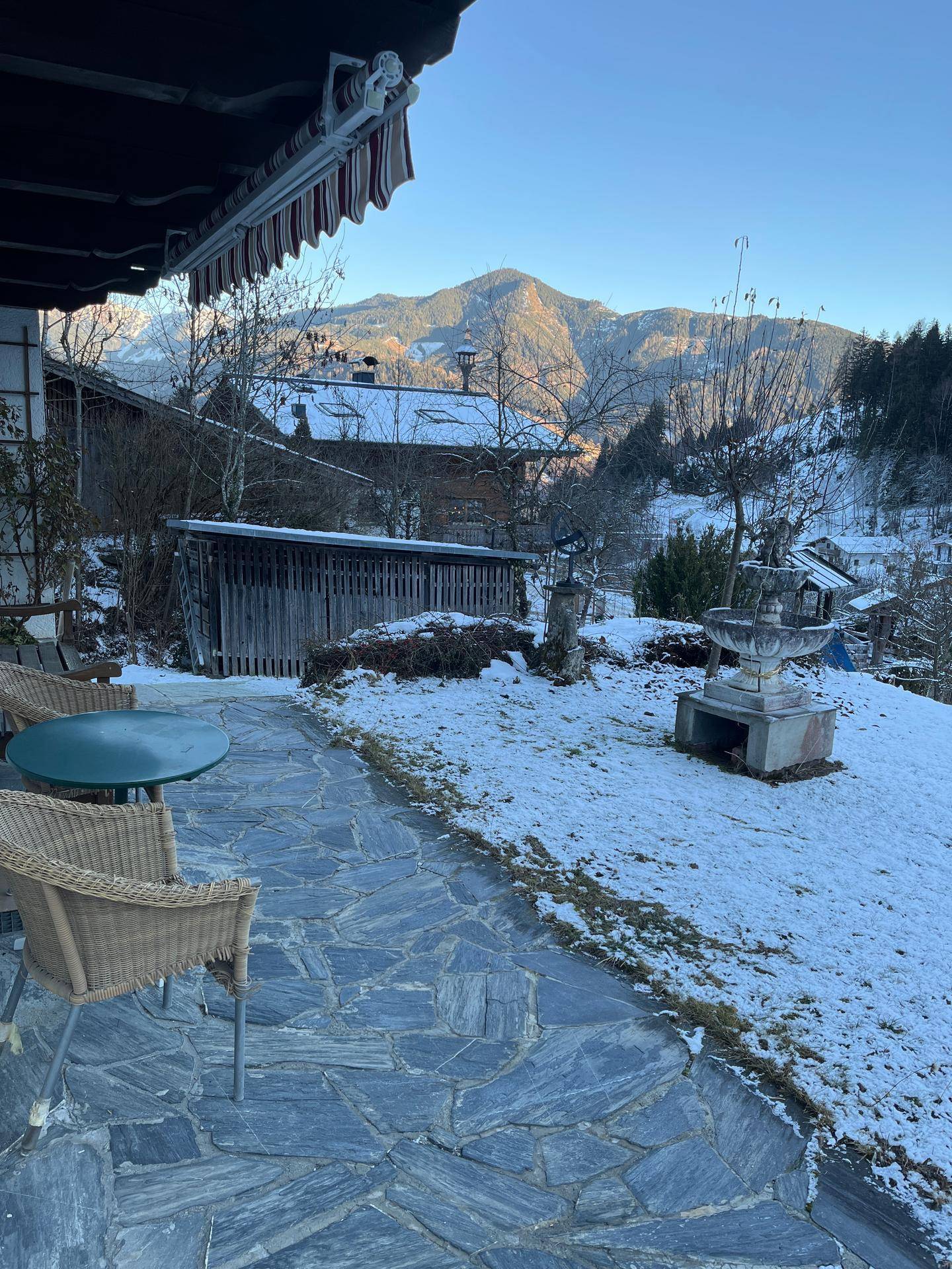 Winterliche Terrasse mit Korbmöbeln und weitem Blick auf die verschneiten Berge.