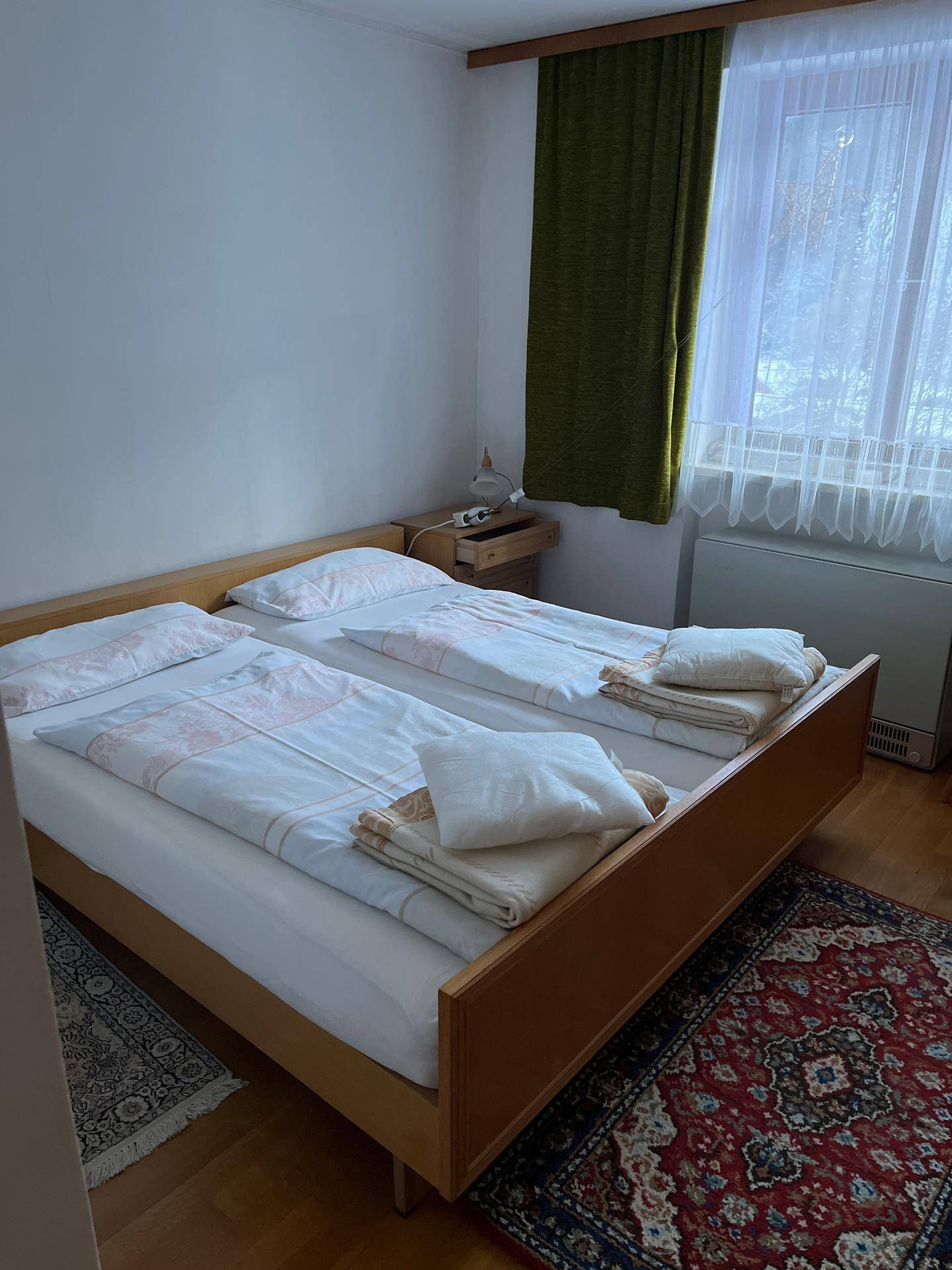 Schlafzimmer mit zwei Einzelbetten, Holzboden und Blick auf die verschneite Landschaft.