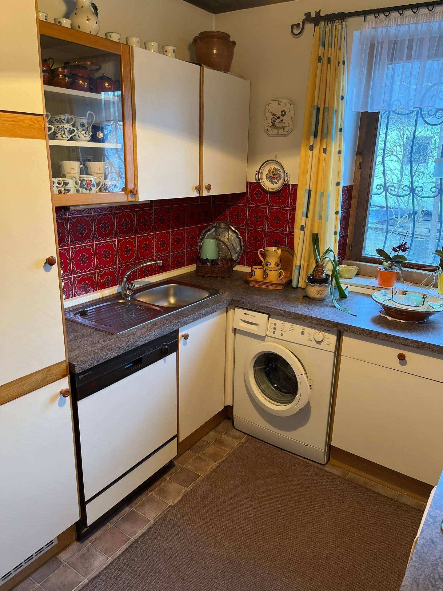 Funktionale Küche mit Spüle, Geschirrspüler und Waschmaschine unter der Arbeitsplatte.