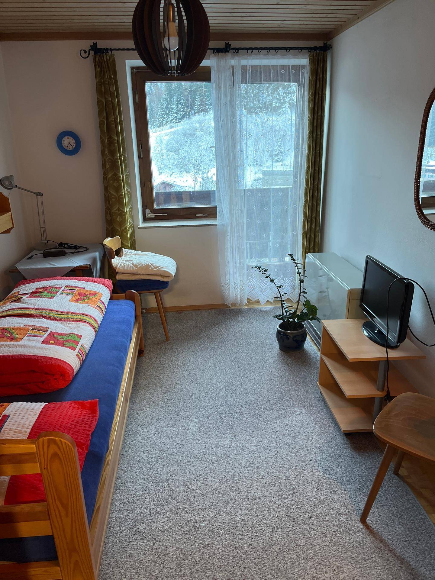 Gemütliches Schlafzimmer mit Einzelbett, Teppichboden und Fenster mit Blick ins Grüne.