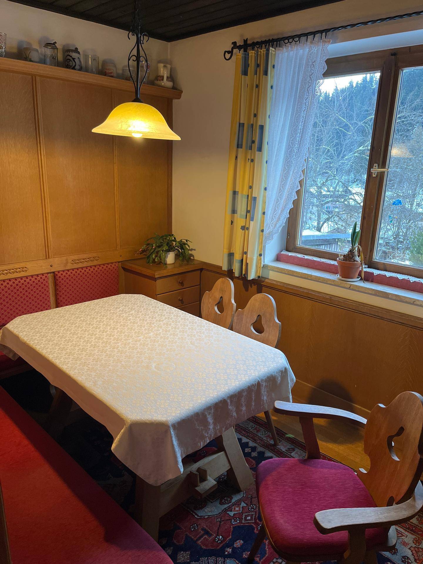 Rustikaler Essbereich mit Holztisch, Eckbank und Blick auf die verschneite Berglandschaft.