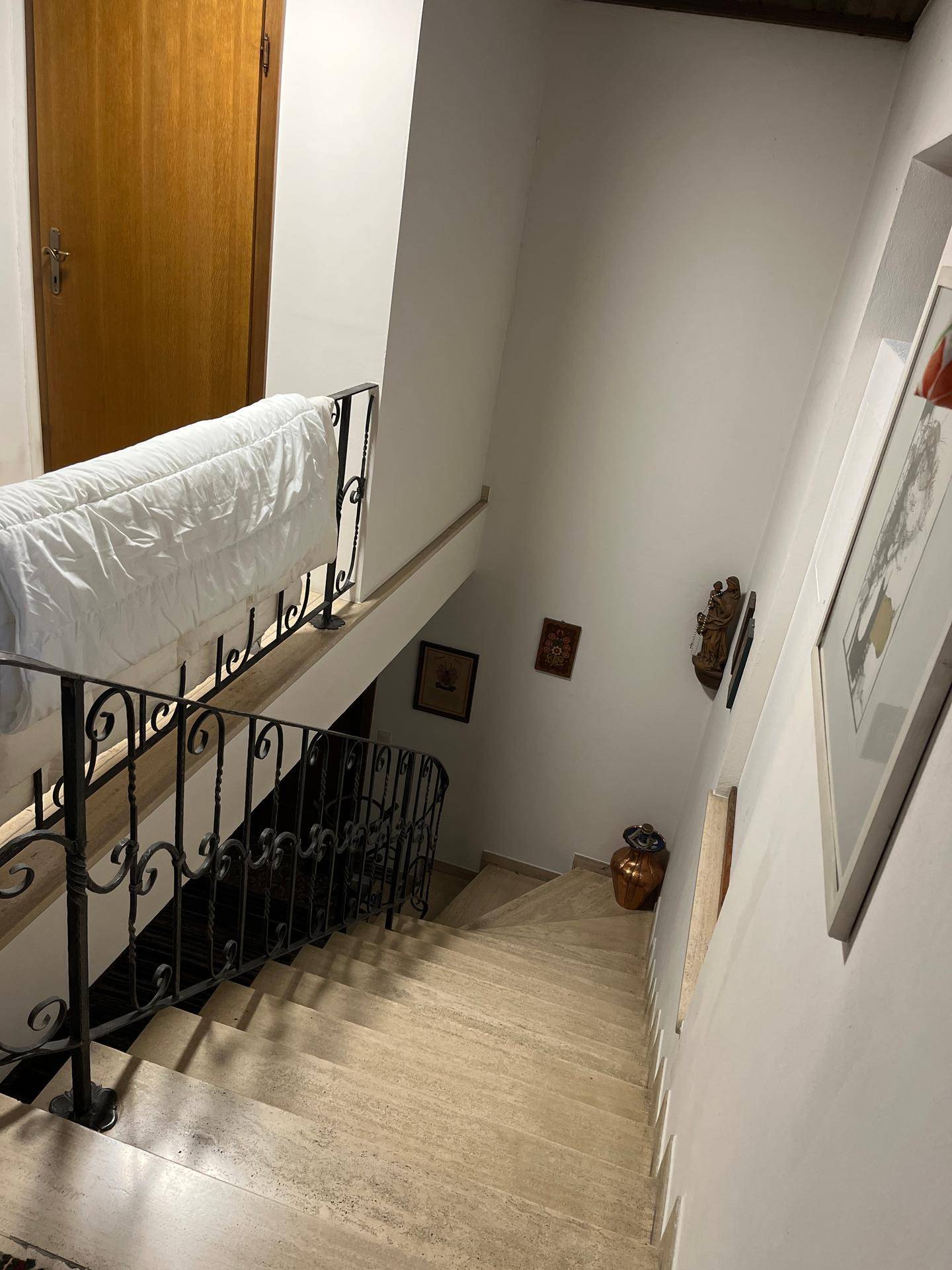 Treppenhaus mit Marmorstufen, schmiedeeisernem Geländer und weiß gestrichenen Wänden.