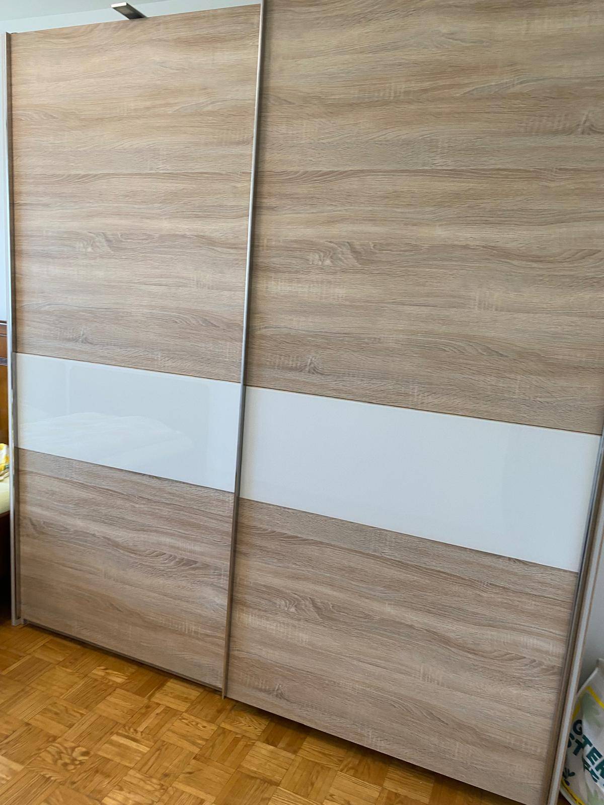 Großer Kleiderschrank mit Holzoptik und weißen Schiebetüren, passend zum Schlafzimmer.