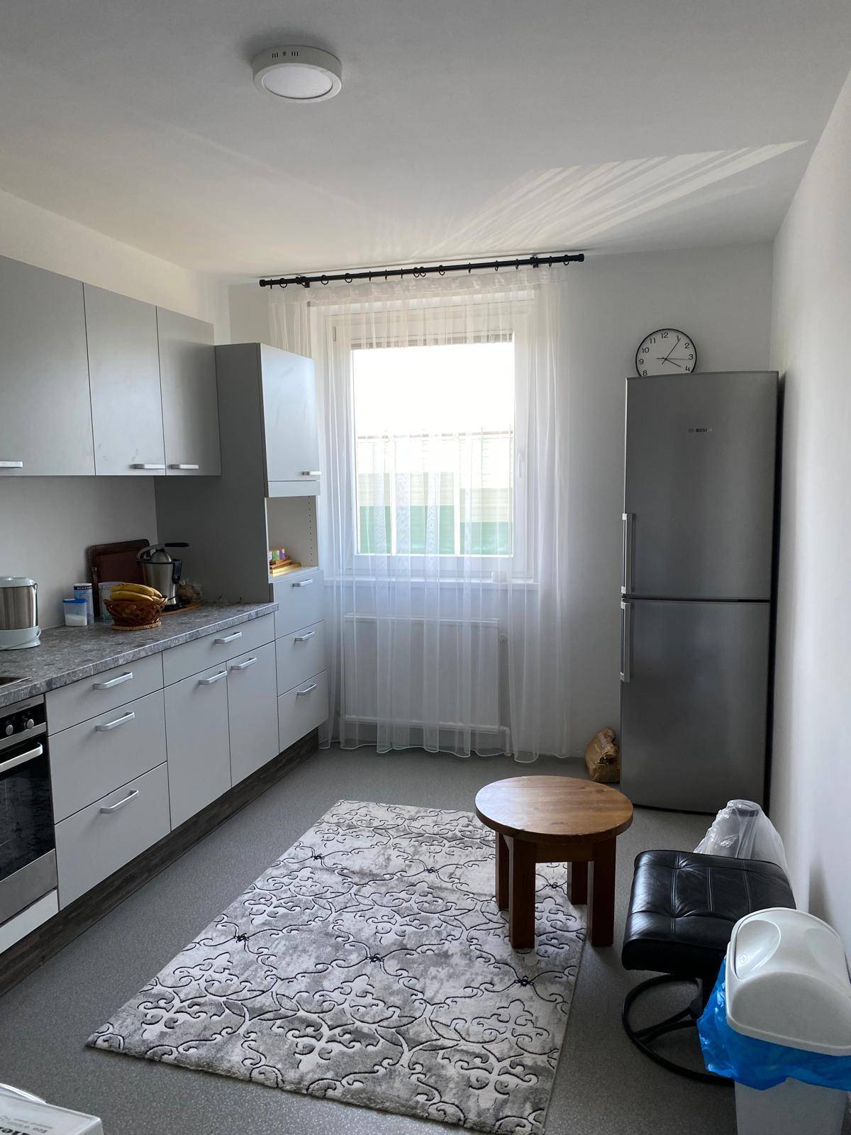 Funktionale Küche mit grauen Schränken, Fenster und einem großen Kühlschrank.