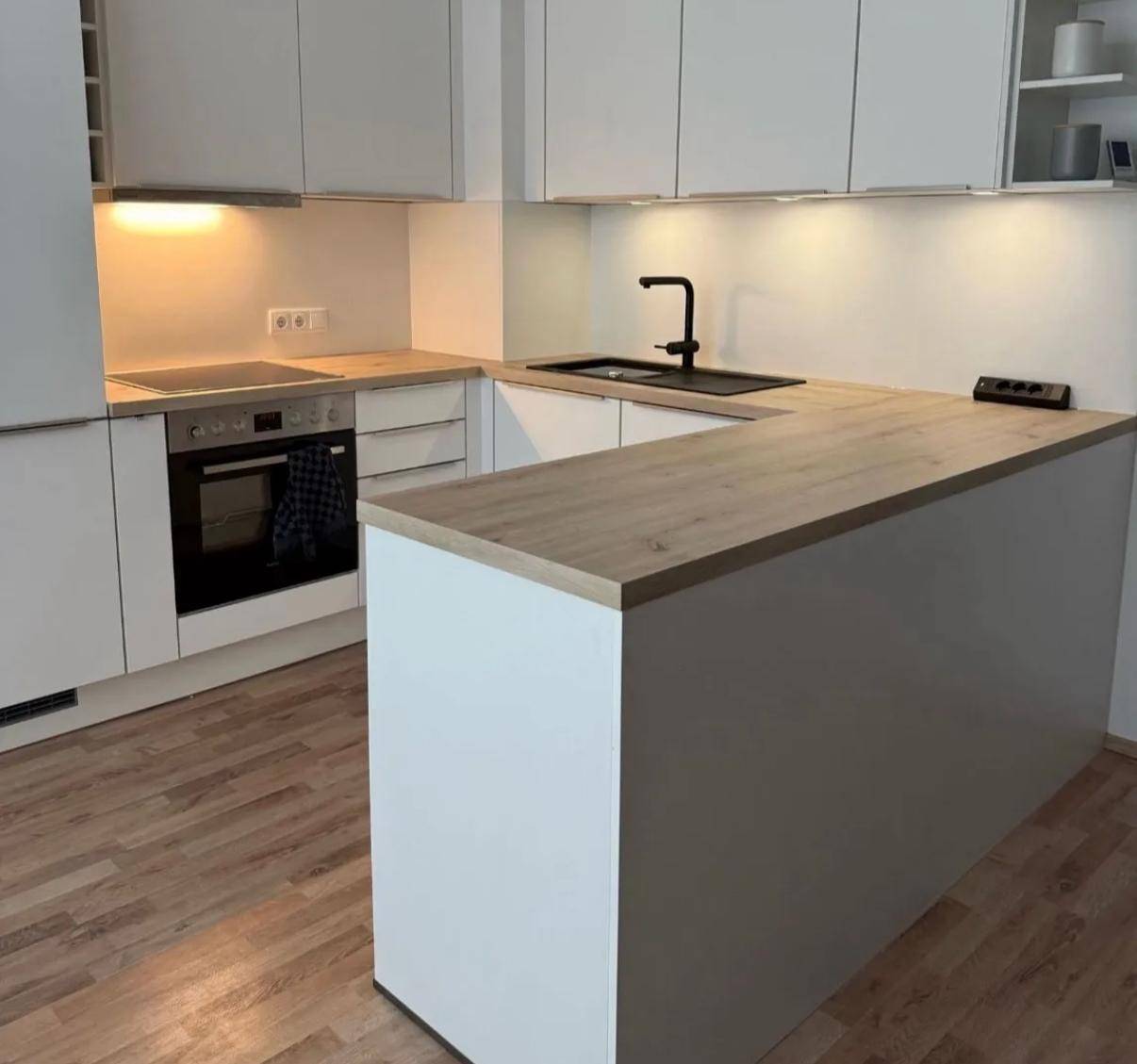 Moderne Einbauküche mit weißen Schränken, Holz-Arbeitsplatten und integrierten Geräten.