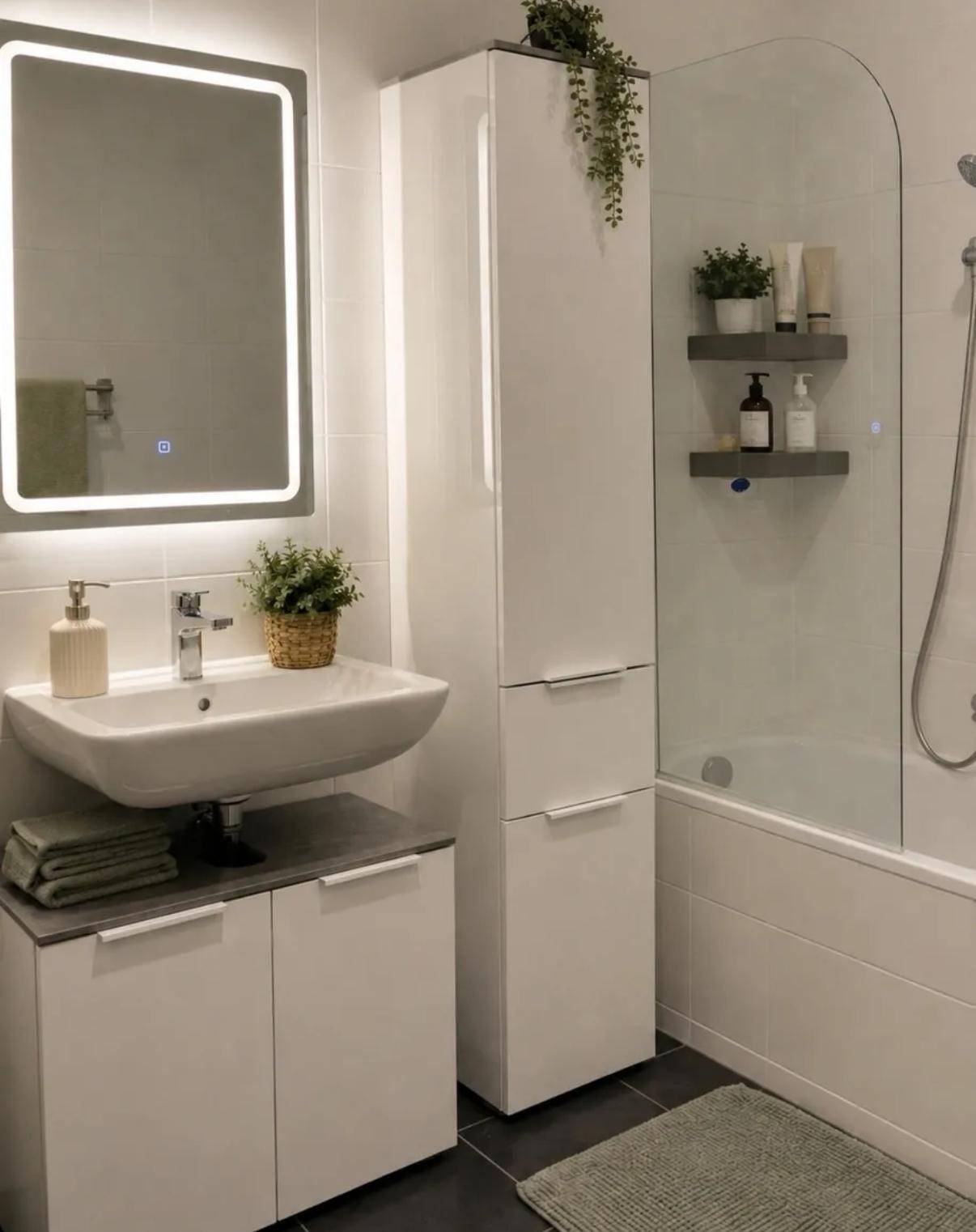 Modernes Badezimmer mit Einzelwaschbecken, beleuchtetem Spiegelschrank und Dusch-Badewannen-Kombination.