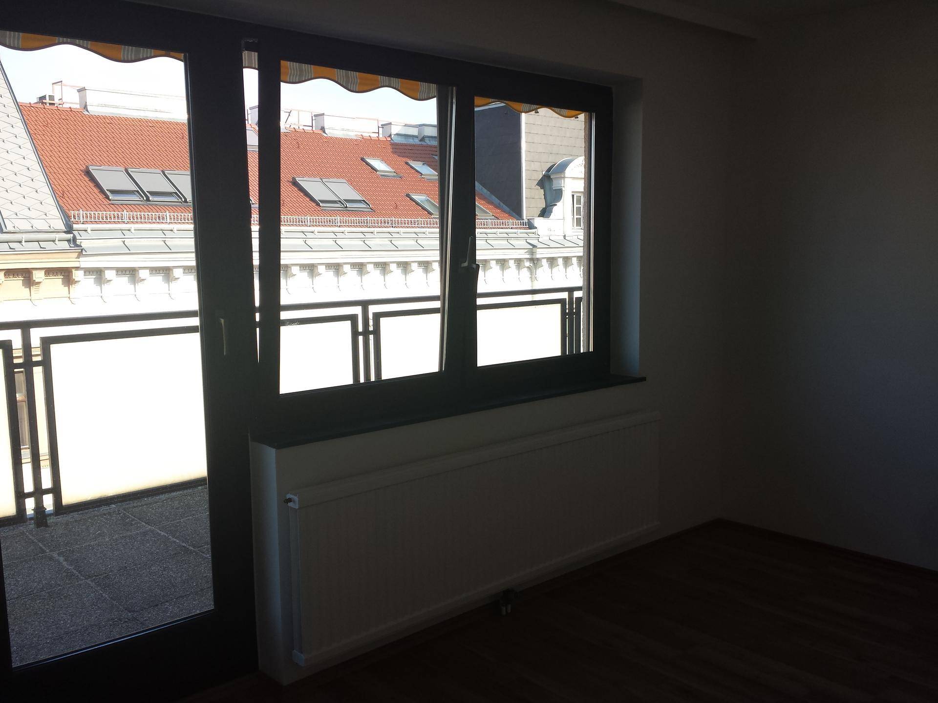 Heller Raum mit Laminatboden, großem Fenster und Zugang zu einem Außenbereich.