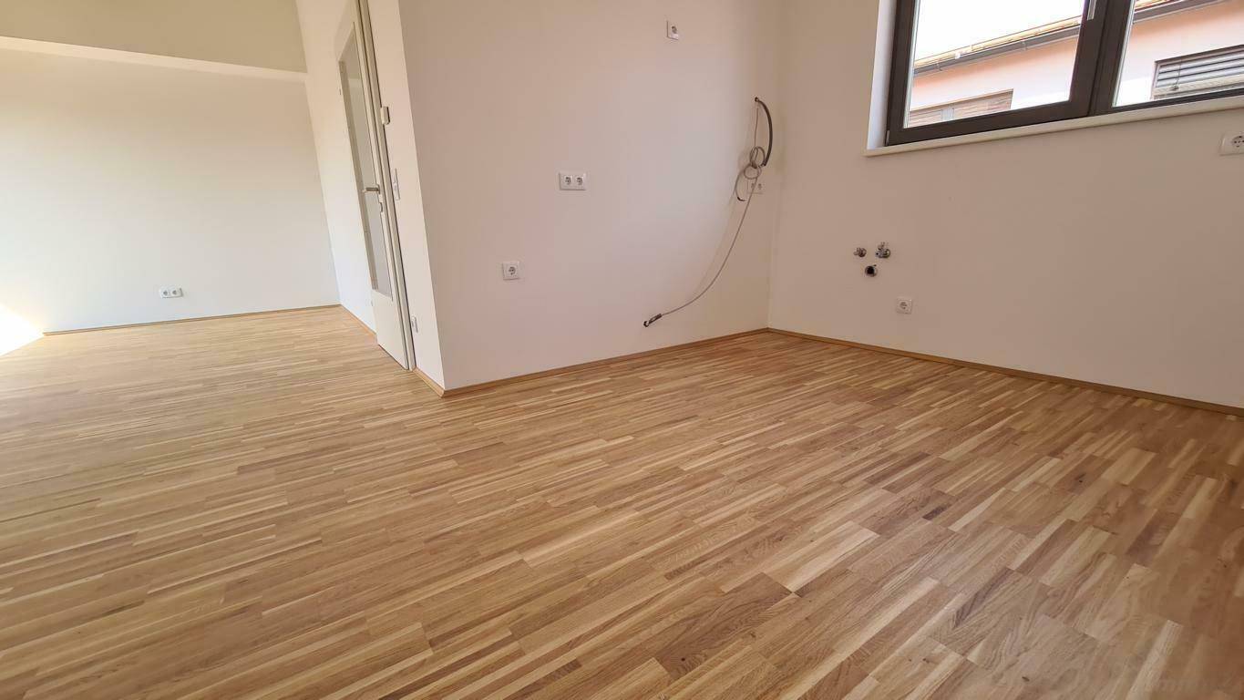 Leerer Küchenbereich im Dachgeschoss mit Anschlüssen für Geräte und Fenster.