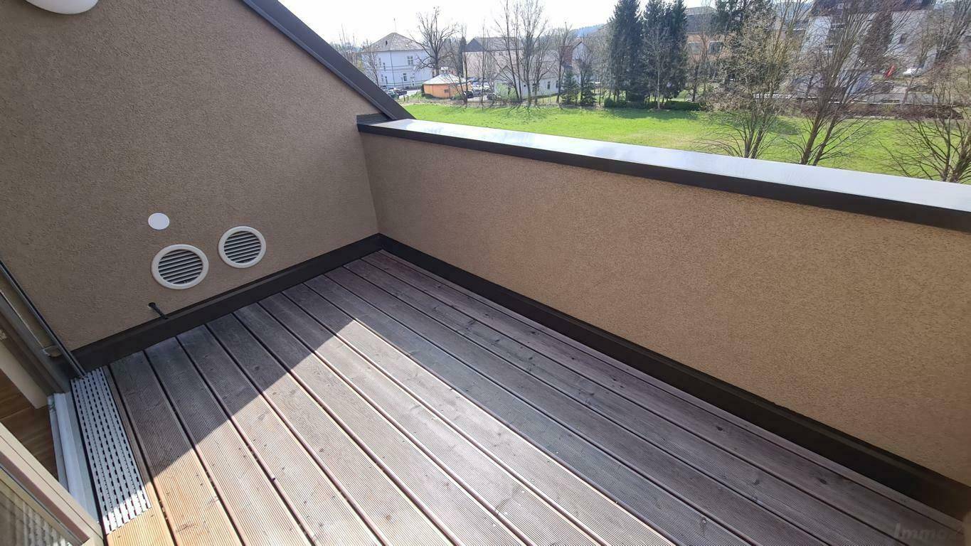 Leere Dachterrasse mit Holzboden und Blick auf die Umgebung.