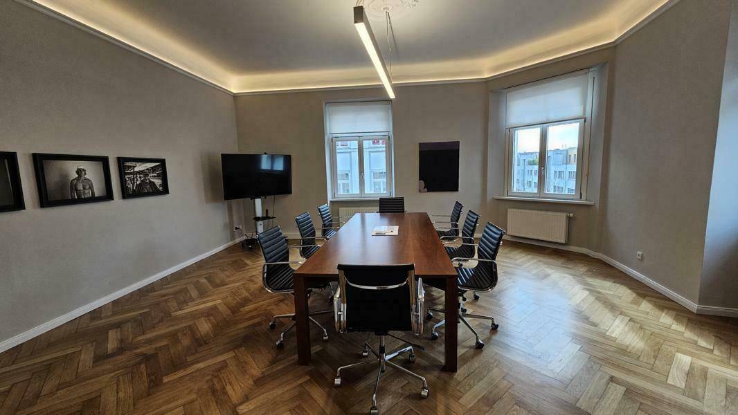 Heller Konferenzraum mit großem Holztisch, bequemen Stühlen und Blick nach draußen.