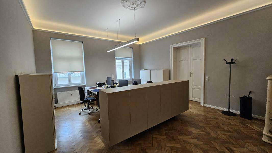 Geräumiges Büro mit mehreren Arbeitsplätzen, Fischgrätparkett und hohen Decken.