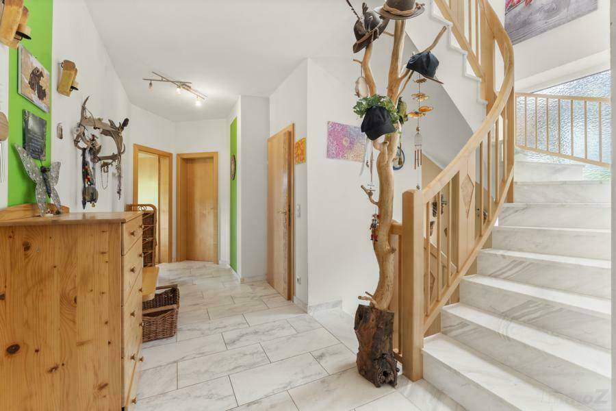 Geräumiger Flur mit heller Marmortreppe, Fliesenboden und Zugang zu weiteren Räumen.