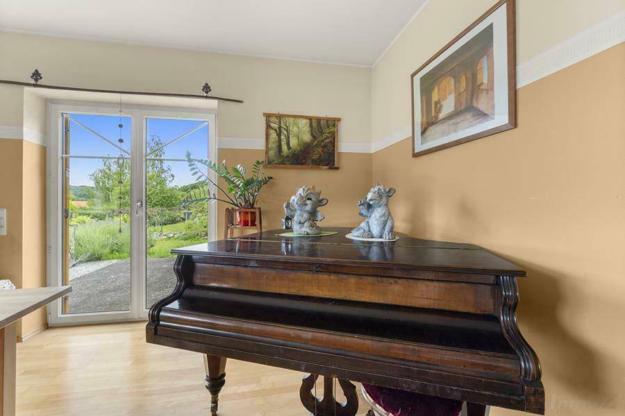Detailansicht des Essbereichs mit Klavier und direktem Zugang zum Garten durch eine Fenstertür.