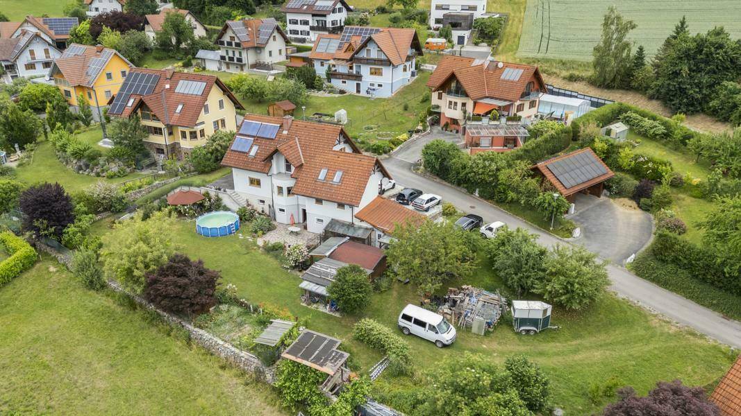 Weitläufige Luftaufnahme einer ländlichen Wohngegend mit Einfamilienhäusern und grünen Gärten.