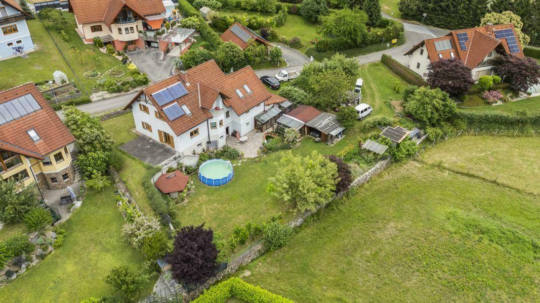 Panoramablick auf eine Wohnsiedlung mit Einfamilienhäusern, umgeben von weitläufigen Grünflächen und Bäumen.