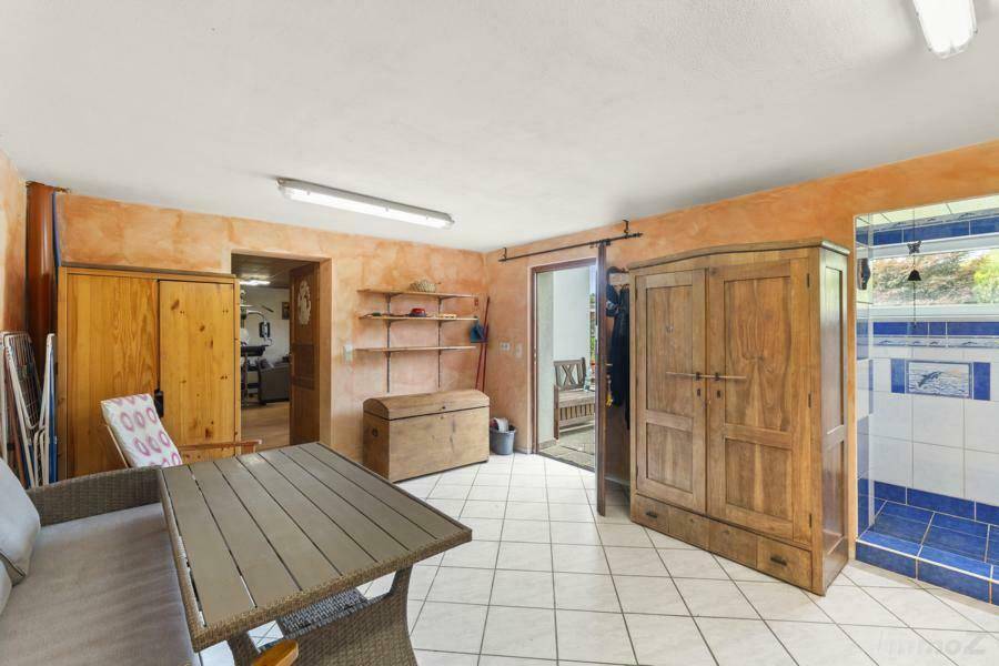 Geräumiger Kellerraum mit Fliesenboden, rustikalen Schränken und direktem Zugang zum Garten.