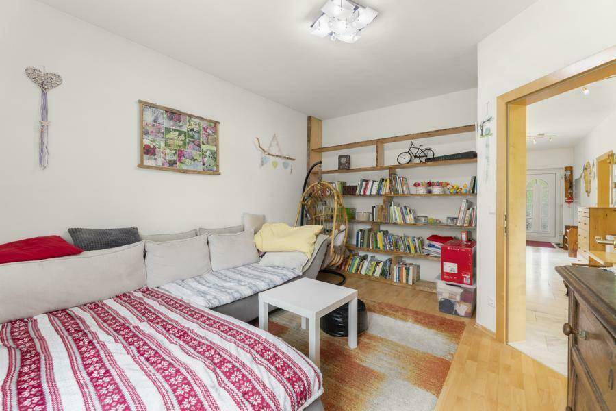 Gemütliches Wohnzimmer mit Sofa, Bücherregal und hellem Holzboden.