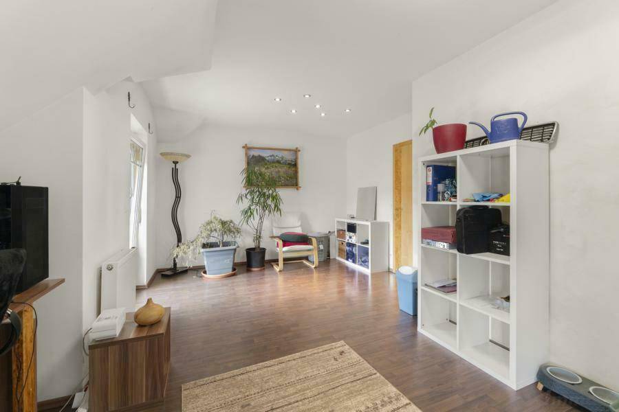 Geräumiges Wohnzimmer im Dachgeschoss mit Laminatboden und viel natürlichem Licht.