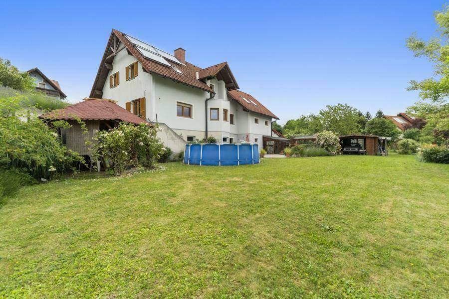 Weitläufiger Garten mit Rasenfläche, Aufstellpool und einem kleinen Gartenhaus im Hintergrund.
