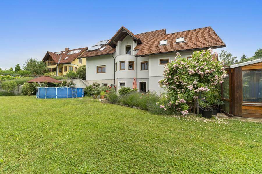 Gepflegter Gartenbereich hinter dem Haus mit Rasen, Aufstellpool und blühenden Rosensträuchern.