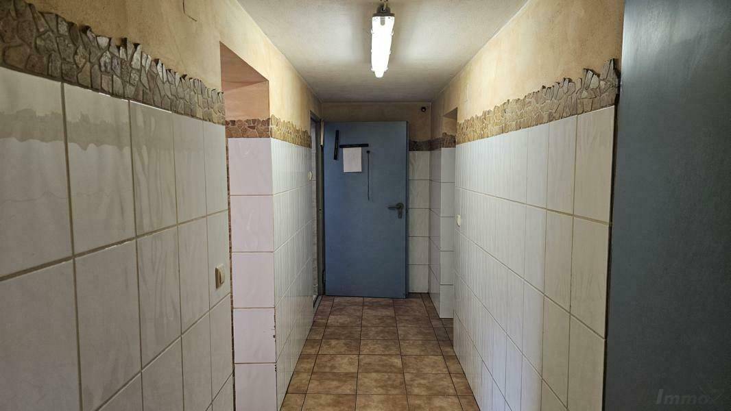 Langer Flur im Kellergeschoss mit gefliesten Wänden und Boden.