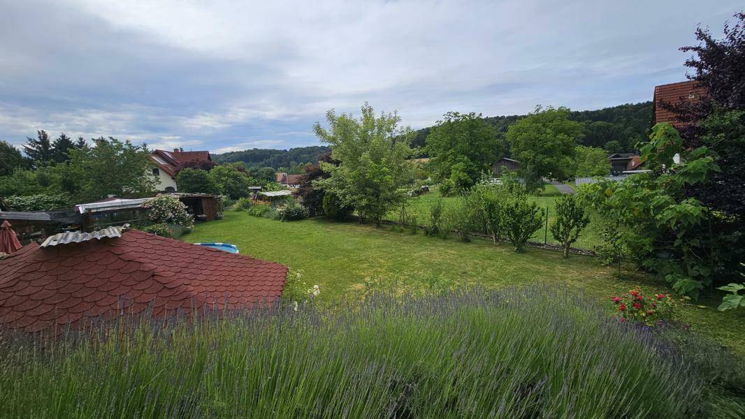 Blühender Lavendel im Vordergrund mit weitem Blick über den grünen Garten und die Landschaft.