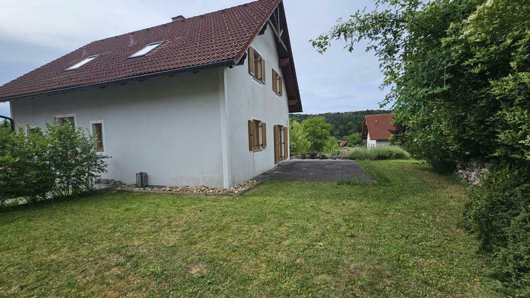 Seitlicher Blick auf das Haus mit einer gepflasterten Terrasse und angrenzender Rasenfläche.