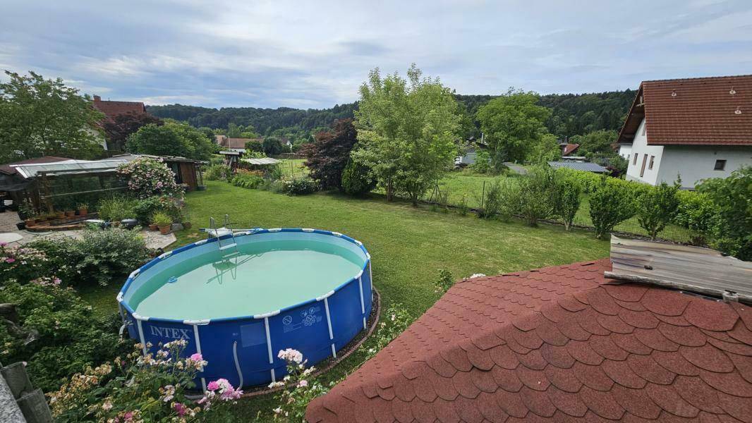 Weitläufiger Garten mit großem Aufstellpool, umgeben von Rasen und Bäumen, von oben betrachtet.
