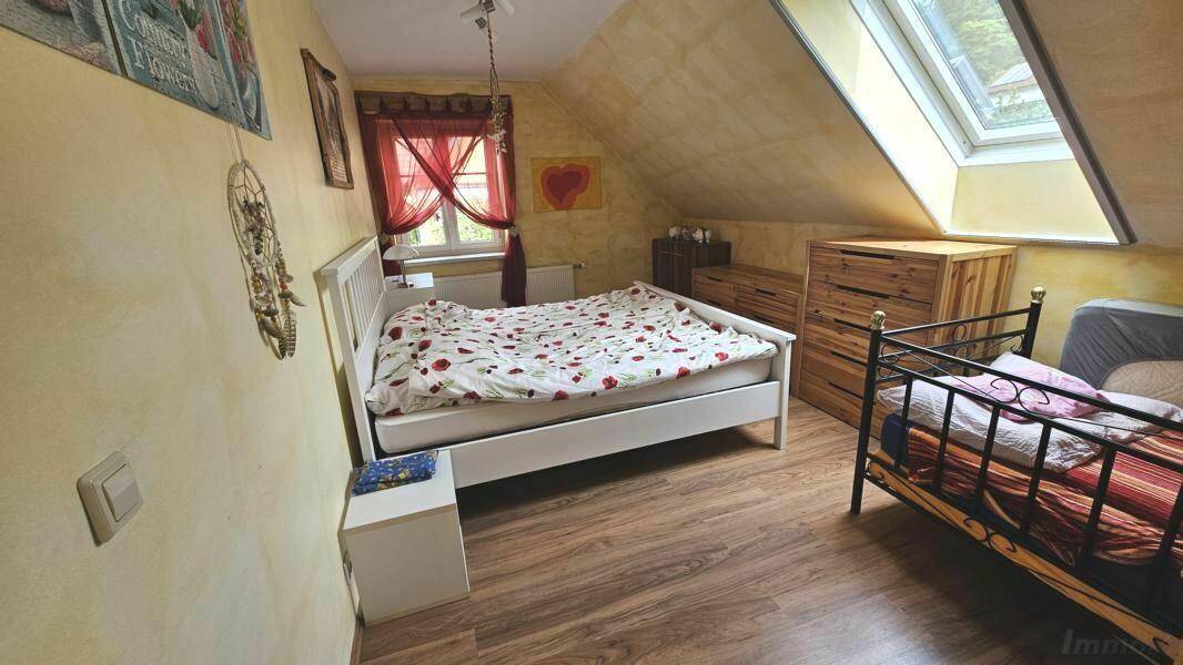 Schlafzimmer im Dachgeschoss mit Dachschräge, Dachfenster und zwei Betten.