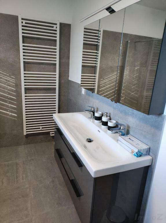 Modernes Badezimmer mit Doppelwaschbecken, Spiegelschrank und Handtuchheizkörper.