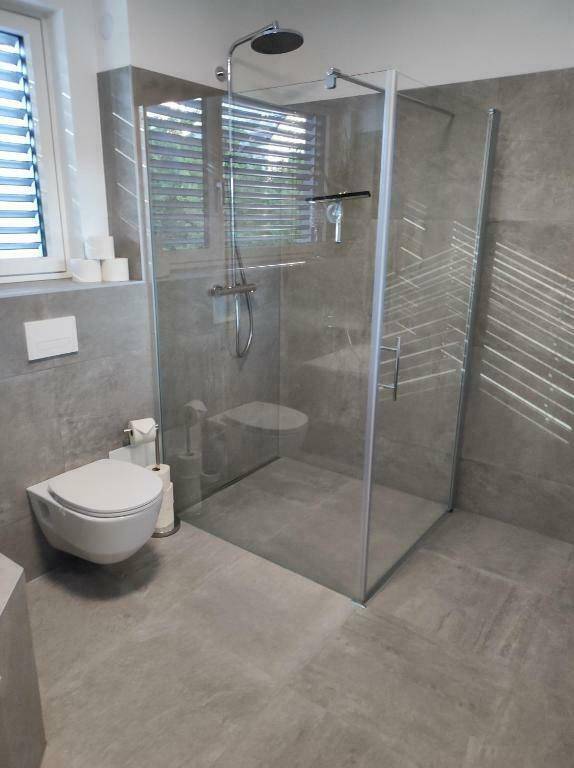Modernes Badezimmer mit ebenerdiger Dusche, Wand-WC und Fenster.