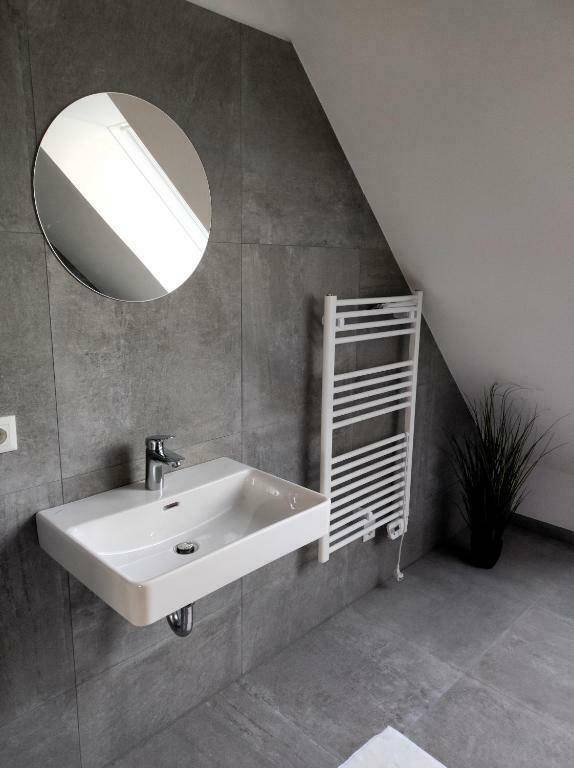 Modernes Badezimmer mit Waschbecken, Spiegel und beheiztem Handtuchhalter.