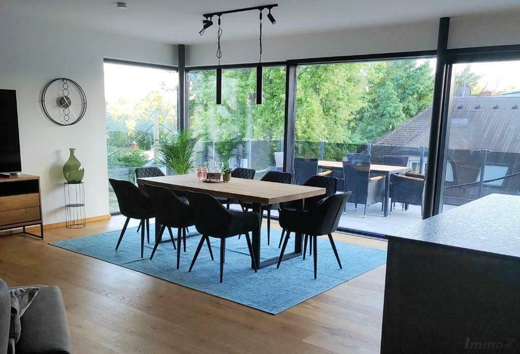 Geräumiger Wohn-Essbereich mit Holzboden, großem Esstisch und Zugang zur Terrasse.