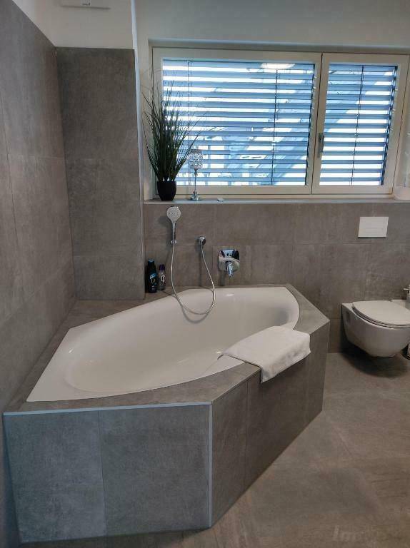Modernes Badezimmer mit Eckbadewanne, Wand-WC und Fenster.