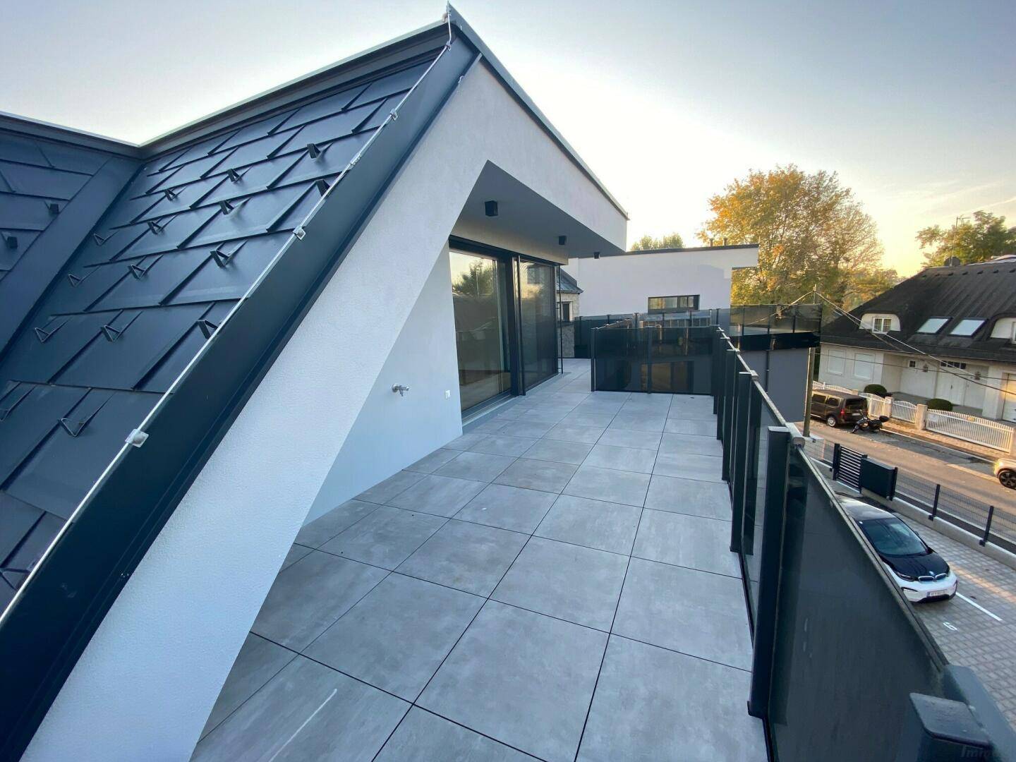 Weitläufige Dachterrasse mit modernen Fliesen und Blick auf die Umgebung.