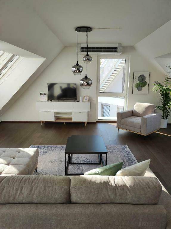 Modernes Wohnzimmer im Dachgeschoss mit Schrägen, Holzboden und Klimaanlage.