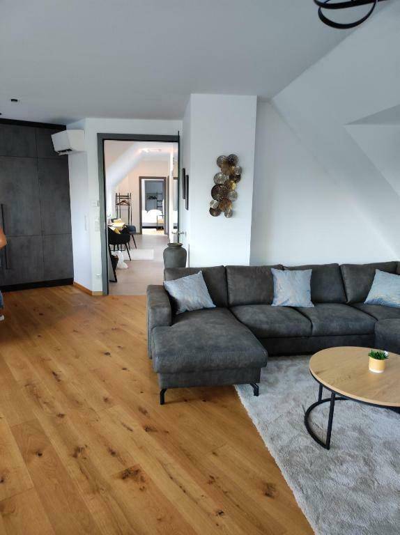 Gemütliches Wohnzimmer mit Holzboden, Ecksofa und Blick in den Flur und weitere Räume.