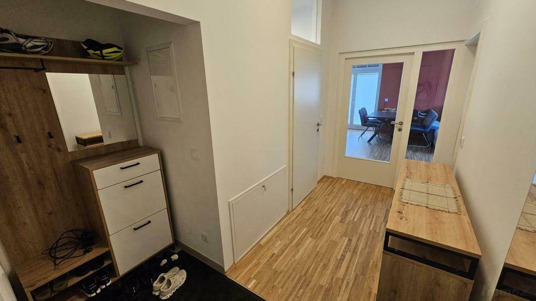 Eingangsbereich mit Garderobe, Holzboden und offenem Zugang zum Wohnbereich.